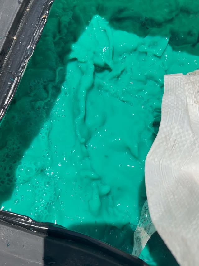 Bright fluorescent turquoise hydroseed slurry inside Gold Class Land Management's tank